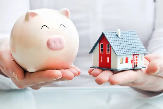 Hands-holding-a-piggy-bank-and-a-house-model - Peak Home Exteriors LLC Hands holding a piggy bank and a house model.